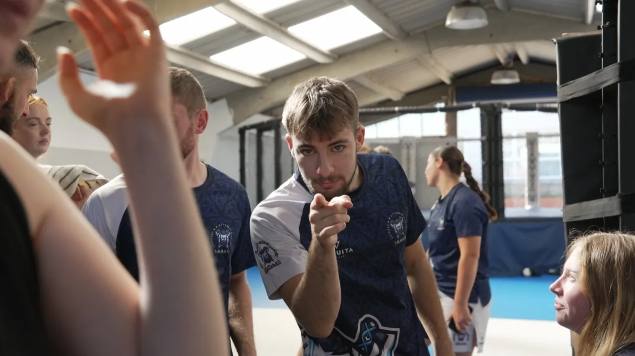 A coach pointing toward the camera during a session at a martial arts gym
