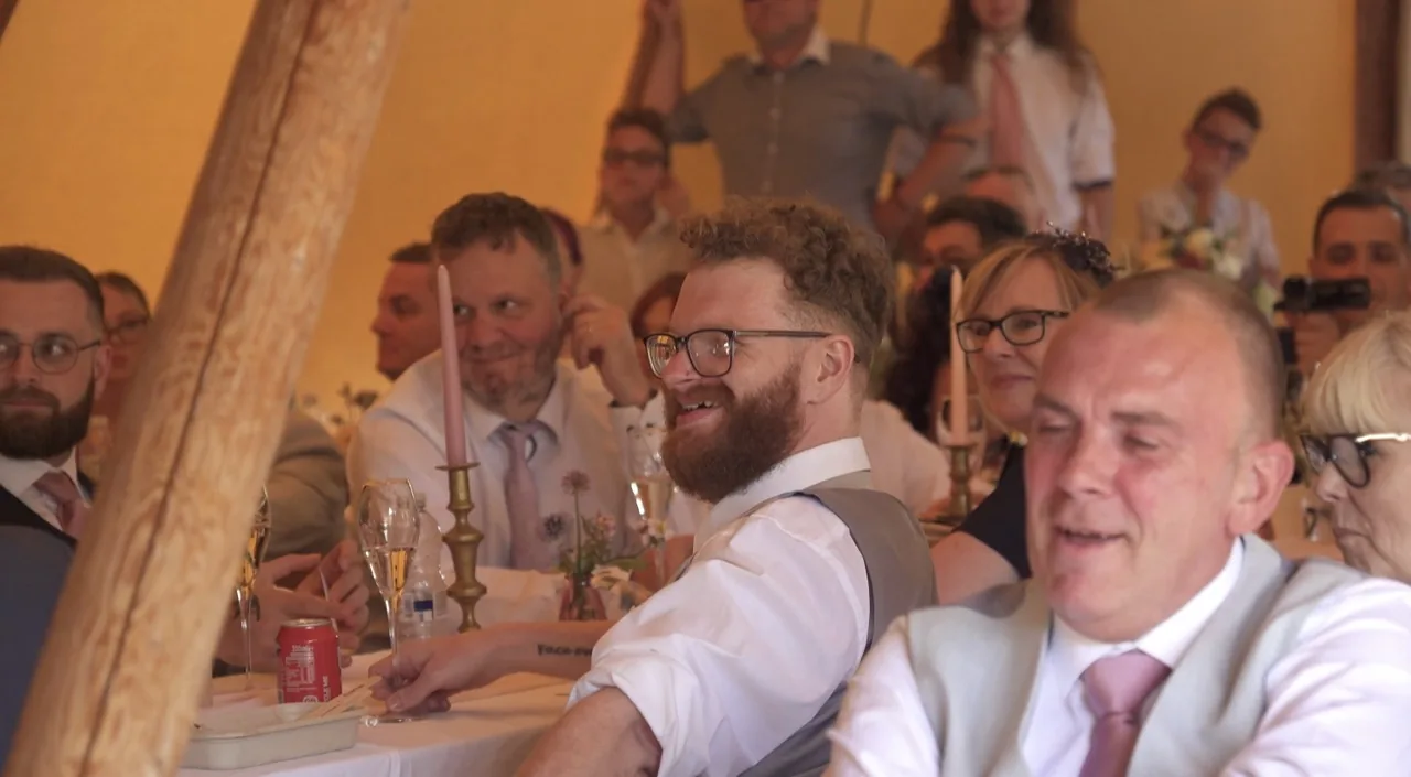 Wedding guests laughing together at their tables during the speeches